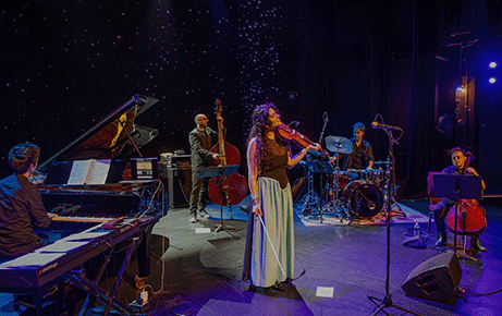 Layale Chaker performs on stage with her ensemble Sarafand, featuring piano, double bass, drums, and cello, under soft stage lighting.