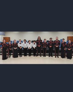 A Mariachi band of students in a line in their traditional red and black costumes.