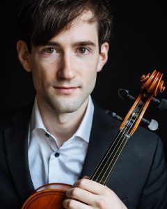 Violist Kyle Miller holding viola and wearing a black suit jacket