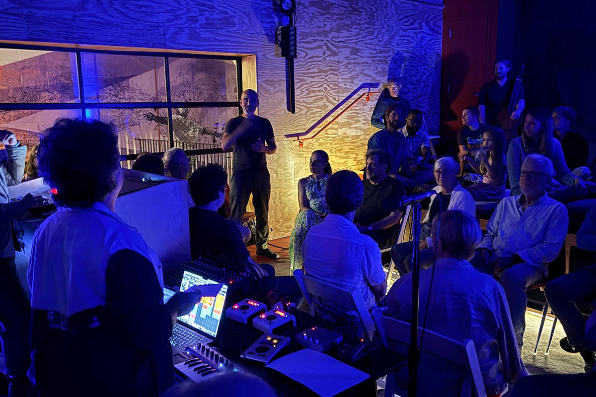 Kinan Azmeh introduces Erdem Helvacioglu in a small room full of audience sitting on the floor and the stage.